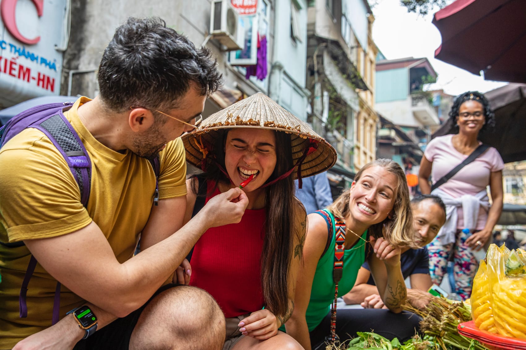 a group of travellers tastes chili peppers at a market 